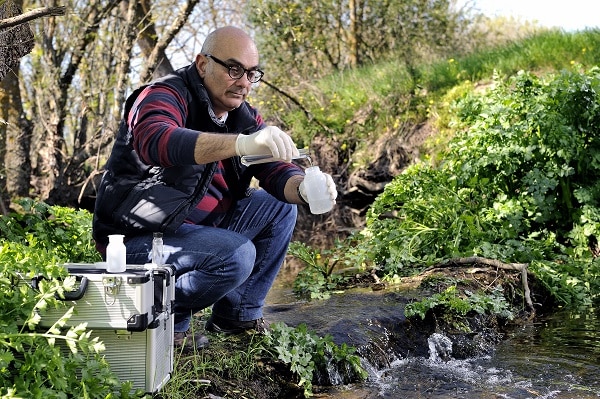 Collecting river water sample for environmental pollution testing